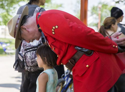 Rob Lockhart, RCMP officer, takes a photo with Kaylee Peebles (five) as she waits in line wait in line to receive her treaty cheque at the Forks in Winnipeg on Tuesday, June 9, 2015. Mikaela MacKenzie / Winnipeg Free Press