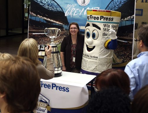 Free Press HR director Dian Trinkaus gets her moment with the Grey Cup and Free Press mascot Scoop at the short visit it had at the Winnipeg Free Press this morning. BORIS MINKEVICH/WINNIPEG FREE PRESS  June 10, 2015