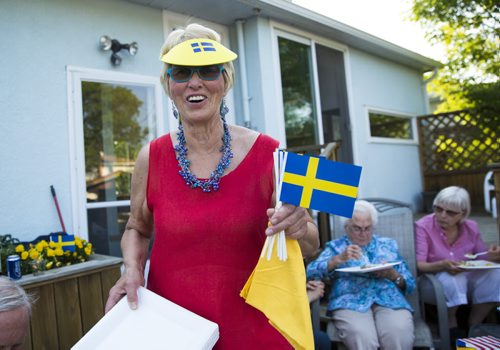 Sonja Lundstrom brings more plates and flags out at a fish fry for soccer fans at Sonja Lundstrom's house on Wednesday, June 10, 2015.  Fried pickerel, maple beans, coleslaw, and homemade bread all made for a typically Canadian meal to serve to the Swedish fans. Mikaela MacKenzie / Winnipeg Free Press
