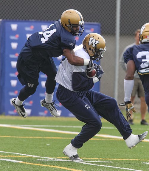 Winston Wright (14) leaps on top of Darvin Adams (4) after he caught the ball during Winnipeg Blue Bombers practice Monday morning.  150615 June 15, 2015 MIKE DEAL / WINNIPEG FREE PRESS