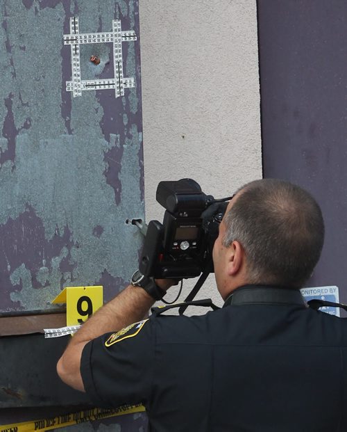 Police have tapped off a large area around Legends Bar & Grill near the Courts of St James apartments at Portage Ave and Woodhaven Blvd after reports of shots fired at 5 AM in the area - Ident officer photographs possible bullet embedded in the  rear of Premier Chiropractic building on Portage Ave near 9am- Breaking News- June 17, 2015   (JOE BRYKSA / WINNIPEG FREE PRESS)