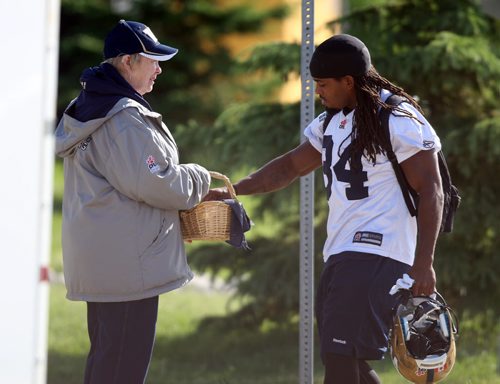 WINNIPEG BLUE BOMBER PRACTICE - Lynn Soens been giving candies to the players as they get to practice for 15 years. Here Ja-Mes Logan gets a little sugar and shares a smile and a few words with the dedicated volunteer. Soens has had season tickets since 1997 too. BORIS MINKEVICH/WINNIPEG FREE PRESS June 17, 2015