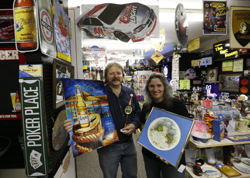 Sunday, This City.  The location is The Rec Room, 377 Henderson Hwy (lower level),  the owners are Glenn and Vera Maskiw.  Vera holds one of her cross stitch scenes and  Glenn has  a tin sign and a beer tap handle.   Dave Sanderson story.   Wayne Glowacki / Winnipeg Free Press June 17  2015