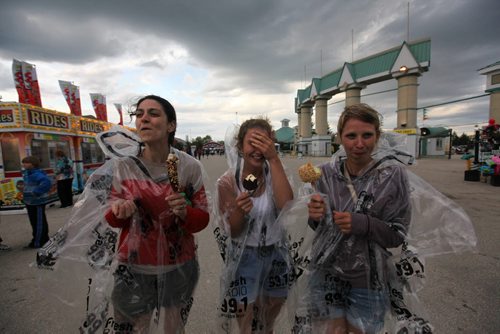 Longtime friends Heather Houston, (left) Marissa Danyluk (centre) and her sister, Teresa Danyluk didn't let the rain, high winds and cold stop them from rekindling a childhood love by going to the Red River Ex, going on rides  and eat ice-cream  Wednesday evening because it may be a long-time before  they can spend time together like this again   Houston  leaves for New Zealand later this summer. See story.   June 17, 2015 Ruth Bonneville / Winnipeg Free Press