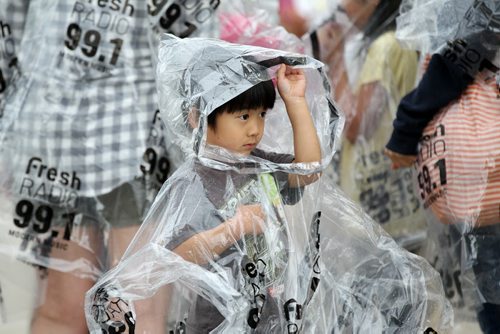 Four-year-old Souta Uesugi holds up his plastic hood on his plastic rain-gear him and his family wear to keep dry from the rain while attending the Red River Ex Wednesday evening.  June 17, 2015 Ruth Bonneville / Winnipeg Free Press