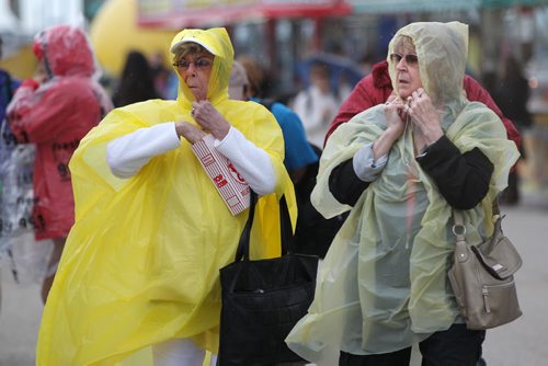 Seniors Iris Kehler (left) and her sister Joyce Rymer cover themselves with rain gear to protect themselves from the high winds and rain as they walk the midway at the Red River Ex Wednesday night.    June 17, 2015 Ruth Bonneville / Winnipeg Free Press