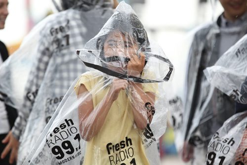Eight-year-old Kanade Uesugi cover her face with a  hood on her plastic rain-gear him and his family wear to keep dry from the rain while attending the Red River Ex Wednesday evening.  June 17, 2015 Ruth Bonneville / Winnipeg Free Press
