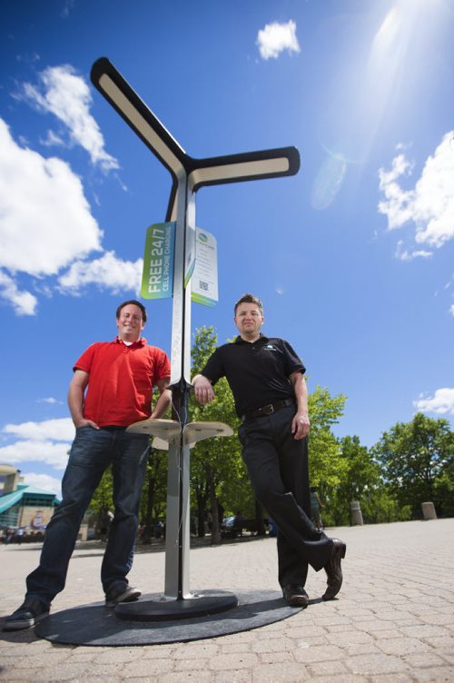Alex Stuart (left) and Justin Phillips, co-founders of Sycamore Inc, stand in front of one of their mobile solar cell phone charging station installation in Winnipeg on Thursday, June 18, 2015.  This station at the Forks is the first of its kind in Canada. Mikaela MacKenzie / Winnipeg Free Press
