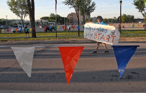 Volunteer Rodger Lourenzo carries a sign prior to the start of the Mini Mites race at the Manitoba Marathon early Sunday morning outside the IGF Stadium.  150621 June 21, 2015 MIKE DEAL / WINNIPEG FREE PRESS