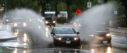 A car ploughs through water collecting in a low stretch on Main Street near Logan Ave. during rain showers Monday morning.  Wayne Glowacki / Winnipeg Free Press June 22  2015