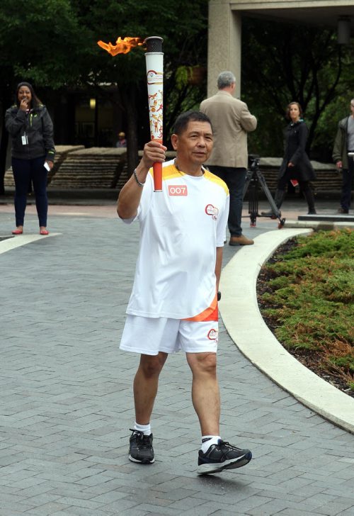 Delfin Tan is the first person that got to run with the torch from the Pan Am Games torch run. He started at City Hall in Winnipeg. BORIS MINKEVICH/WINNIPEG FREE PRESS June 22, 2015