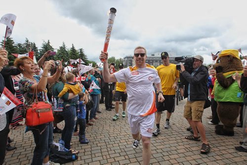 Olympian Jon Montgomery runs the Pan Am Torch through the crowd at The Forks for a cauldron lighting ceremony Monday afternoon.  150622 June 22, 2015 MIKE DEAL / WINNIPEG FREE PRESS