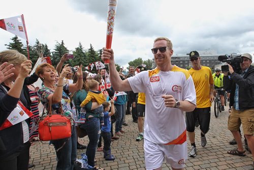 Olympian Jon Montgomery runs the Pan Am Torch through the crowd at The Forks for a cauldron lighting ceremony Monday afternoon.  150622 June 22, 2015 MIKE DEAL / WINNIPEG FREE PRESS