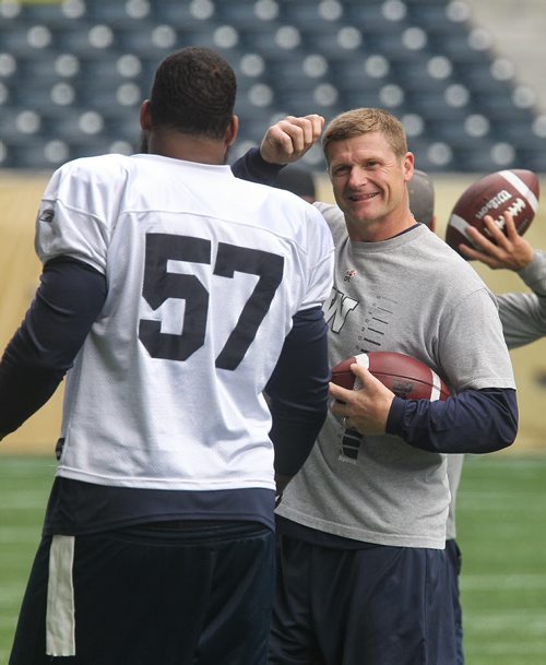 Head coach Mike O'Shea jokes with Devin Tyler (57) during warm-up at morning practice in IGF Monday.  150623 June 23, 2015 MIKE DEAL / WINNIPEG FREE PRESS