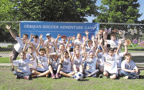 Canstar Community News June 18, 2015 - Ulla In der Stroth (standing left) and Oliver Fiest, (standing far right), a visiting Auf Ballhohe soccer coach from Munich, Germany, pose with a group of Grade 4 German Bilingual program students at Princess Margaret School during the RETSD's week long German soccer camp. (SHELDON BIRNIE/CANSTAR COMMUNITY NEWS/THE HERALD)