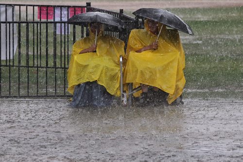 Gary and Louise Watson endure the downpour at the Festival Stage at The Forks while waiting for the United Way 50th Anniversary concert, One Night For Winnipeg to start. The concert has been delayed, but should start at 7pm.  150624 June 24, 2015 MIKE DEAL / WINNIPEG FREE PRESS