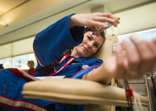 START flight nurse Jennifer Fosty checks out where her blood is going while giving blood as part of the Sirens for Life initiative at the Canadian Blood Services in Winnipeg on Thursday, June 25, 2015. Mikaela MacKenzie / Winnipeg Free Press