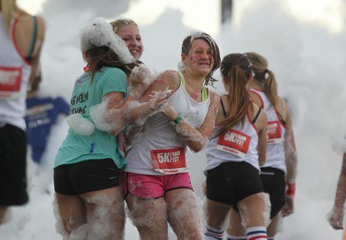 A group of girls make their way through a wall of foam at the start gate of Adrenaline Adventures, Foam Fest, a funny 5k obstacle course that takes participants through mud, rope climbs and bouncers Saturday.  Standup photo   June 27,, 2015 Ruth Bonneville / Winnipeg Free Press