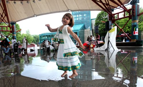 Four-year-old Elena Heide decides to dance in her bare feet after a downpour of rain left a huge puddle under the canopy at the Forks Saturday.   Standup photo   June 27,, 2015 Ruth Bonneville / Winnipeg Free Press