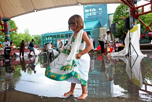 Four-year-old Elena Heide decides to take her shoes off and dance in her bare feet after a downpour of rain left a huge puddle under the canopy at the Forks Saturday.   Standup photo   June 27,, 2015 Ruth Bonneville / Winnipeg Free Press