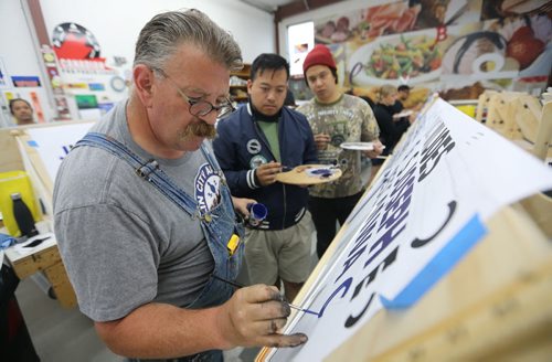 Mike Meyer instructs Joseph Pilapio and Jan Castillo. Meyer was brought in to instruct a sign painting workshop at Signmeister, Saturday, June 27, 2015. The art of hand sign painting has been making a resurgence after nearly becoming obsolete due to computers and vinyl. (TREVOR HAGAN/WINNIPEG FREE PRESS)