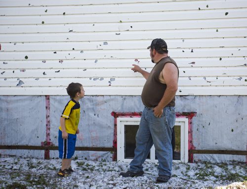 Deric Peters shows his son, Austin, the hail damage on their house just north of Roseisle, Manitoba on Saturday, June 27, 2015.   Mikaela MacKenzie / Winnipeg Free Press