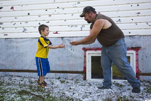 Deric Peters shows his son, Austin, the hail damage on their house just north of Roseisle, Manitoba on Saturday, June 27, 2015.   Mikaela MacKenzie / Winnipeg Free Press