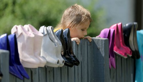 Katrina Thorne, 4, peaks over at a yard sale along Corydon Avenue, Sunday, June 28, 2015. (TREVOR HAGAN/WINNIPEG FREE PRESS)