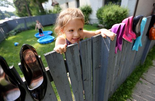 Katrina Thorne, 4, peaks over at a yard sale as her friend, Xavier Kowbel cools off in a pool along Corydon Avenue, Sunday, June 28, 2015. (TREVOR HAGAN/WINNIPEG FREE PRESS)