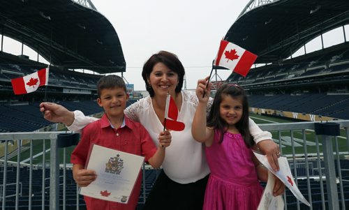 Hysnije Krasnigi with her children Dion,7, at left and Dea,5, originally from Kosovo were among the 100 people that became Canadians at the Citizenship Ceremony in the Pinnacle Club at Investors Group Field Monday. The new Canadians were treated to tickets for the Winnipeg Blue Bombers Home Opener on July 2nd  and will  be honoured at the  special half-time presentation with the citizens at centre field. ¤  see release .Wayne Glowacki / Winnipeg Free Press June 29  2015