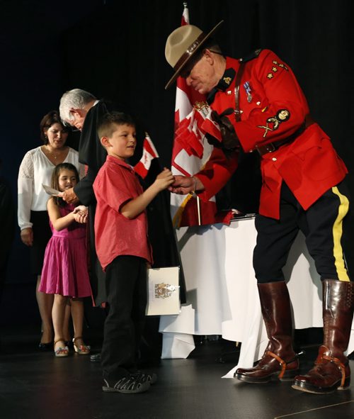 At right,  Dion Krasnigi,7, receives a flag from retired RCMP Const. Ray Steen as his sister Dea,4, and mother Hysnije meet Judge James McCrae ,  the family members originally from Kosovo  were among the 100 people that became Canadians at the Citizenship Ceremony in the Pinnacle Club at Investors Group Field Monday. The new Canadians were treated to tickets for the Winnipeg Blue Bombers Home Opener on July 2nd  and will be honoured at the special half-time presentation with the citizens at centre field. ¤  see release .Wayne Glowacki / Winnipeg Free Press June 29  2015