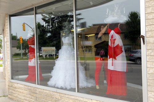 STANDUP - Carly Iskierski does some adjusting to the Canada Day fashion displayed in the 7th Avenue Fashion shop on Academy. BORIS MINKEVICH/WINNIPEG FREE PRESS June 30, 2015