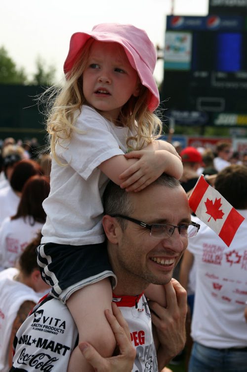 Four year old Ella Andrews gets a great view of the Human Canadian Flag on top of her dad Rod Salm's shoulders at Shaw baeball park. BORIS MINKEVICH/WINNIPEG FREE PRESS July 1, 2015