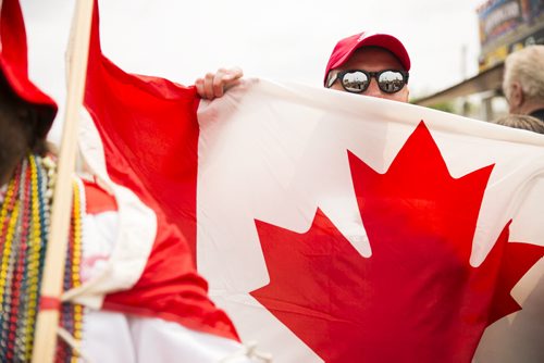 Mark Joss peeks over his friend's Canadian flag cape at the annual Osborne Street Festival on Wednesday, July 1, 2015. Mikaela MacKenzie / Winnipeg Free Press