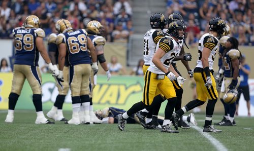 The Hamilton Tiger-Cats'  celebrate and the Winnipeg Blue Bombers' look on with concern after Taylor Reed (44) and Adrian Tracy (93) sacked Winnipeg Blue Bombers' quarterback Drew Willy (5). Willy would be hurt on the play and be forced to leave the game. Thursday, July 2, 2015. (TREVOR HAGAN/WINNIPEG FREE PRESS)