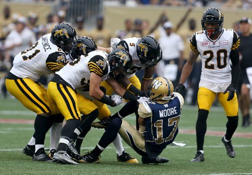 Winnipeg Blue Bombers' Nick Moore (17) is brought down by a pack of Hamilton Tiger-Cats'  during first half CFL action, Thursday, July 2, 2015. (TREVOR HAGAN/WINNIPEG FREE PRESS)