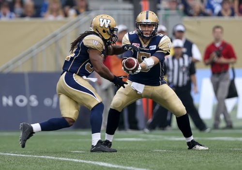 Winnipeg Blue Bombers' quarterback Drew Willy (5) hands the ball of to Paris Cotton (34) before getting hurt while playing against the Hamilton Tiger-Cats'  during first half CFL action, Thursday, July 2, 2015. (TREVOR HAGAN/WINNIPEG FREE PRESS)