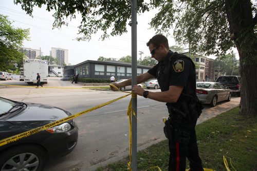 A police officer keeps bystanders back from the Petersen and King Law Office at 252 River Ave. as officers officers take a close look at the window using a flashlight which appears to be broken and blood sprayed Friday afternoon.  See story.  July 03,, 2015 Ruth Bonneville / Winnipeg Free Press