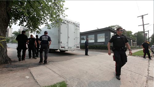 Police officers gather around Petersen and King Law Office at 252 River Ave. late Friday afternoon to take a closer look at the scene of a bomb that went off Friday morning in the hands of one of the workers in the office.  She was taken to hospital in critical condition.    See story.  July 03,, 2015 Ruth Bonneville / Winnipeg Free Press