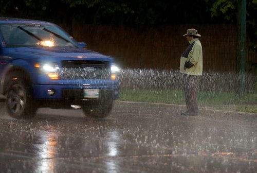 A pedestrian wait to cross Marion Street during a heavy downpour, Saturday, July 4, 2015. (TREVOR HAGAN/WINNIPEG FREE PRESS)