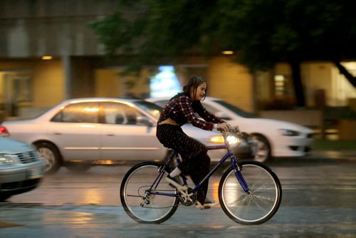 A cyclist rides along Marion Street during a heavy downpour, Saturday, July 4, 2015. (TREVOR HAGAN/WINNIPEG FREE PRESS)