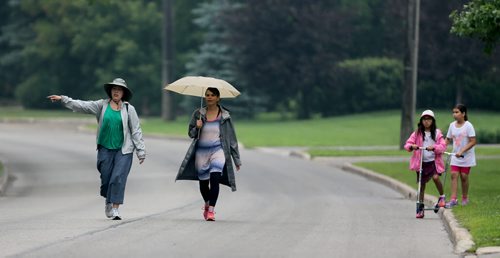 Roberta Stout signals to oncoming traffic while walking with her friend, Lorena Fontaine, and each of their daughters, Sarah Fontaine-Sinclair, 9 and Miya Wata, 9. Traffic on Wellington Crescent, which is supposed to be limited to only one block, Sunday, July 5, 2015. (TREVOR HAGAN/WINNIPEG FREE PRESS)