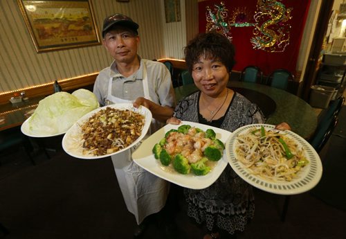 Owners Yan Ping Cao (right) and Wan Duo Li show off dishes (from left) Super Snow Dish (with lettuce wraps), stir-fried Crystal Shrimp with garlic and Mooshi chicken at Dragon Palace at 3060 Portage Ave. Photographed for restaurant review. Photo by Jason Halstead/Winnipeg Free Press