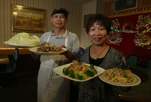 Owners Yan Ping Cao (right) and Wan Duo Li show off dishes (from left) Super Snow Dish (with lettuce wraps), stir-fried Crystal Shrimp with garlic and Mooshi chicken at Dragon Palace at 3060 Portage Ave. Photographed for restaurant review. Photo by Jason Halstead/Winnipeg Free Press