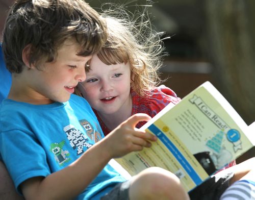Two and a half-year-old, Eloise Lamont looks over her older brother Ronan's shoulder (7yrs), as he reads a book he picked up from the library earlier in the day in Cordova Park Tuesday afternoon.    July 07, 2015 Ruth Bonneville / Winnipeg Free Press