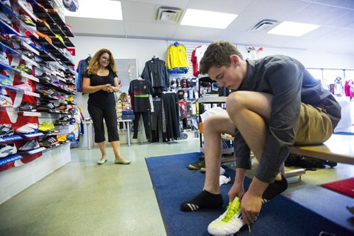 Cecilia Castro, owner of La Liga soccer shop, helps Alex Vonhof try on cleats in her store in Winnipeg on Wednesday, July 8, 2015.   Mikaela MacKenzie / Winnipeg Free Press