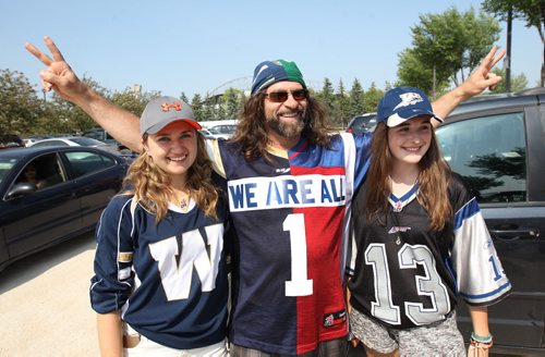 Tail Gating- Erwin Denishuk, centre, made a jersey half Bombers half Alouettes as he is taking his daughter Alexis Denishuk , left,and exchange student  whi is boarding with them Florence Cote, right, to Investors Group Field Friday  Standup Photo- July 10, 2015   (JOE BRYKSA / WINNIPEG FREE PRESS)