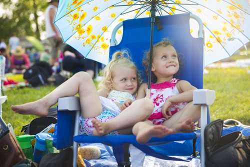 Abby (left) and Bell Moravcik, three-year-old twins, enjoy the shade from their parasol at the Winnipeg Folk Festival in Birds Hill Park on Friday, July 10, 2015.   Mikaela MacKenzie / Winnipeg Free Press