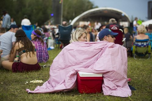 Elensia Herda and Jordan DeVisser cuddle under a poncho to keep dry at the Winnipeg Folk Festival at Birds Hill Provincial Park on Saturday, July 11, 2015.   Mikaela MacKenzie / Winnipeg Free Press