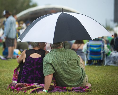 Marilyn Fehr and Robert McKenzie share an umbrella at the Winnipeg Folk Festival at Birds Hill Provincial Park on Saturday, July 11, 2015.   Mikaela MacKenzie / Winnipeg Free Press